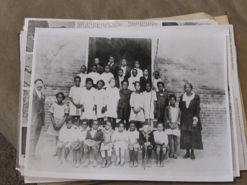 A black-and-white photo of Black boys and girls of various ages, as well as a male and female adult, who are posed for a school photo.