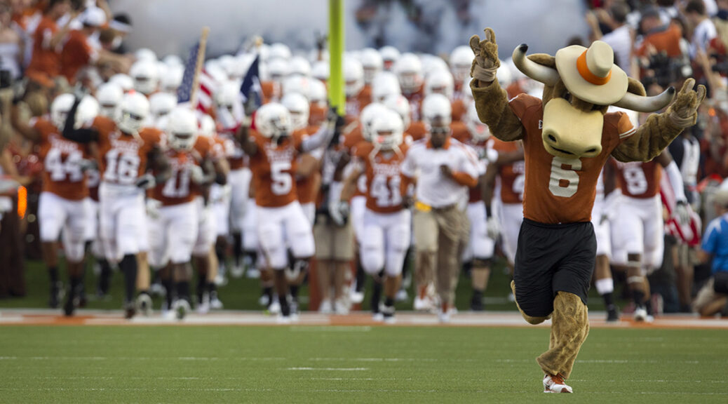 the ut mascot, hook 'em, leads longhorn football players onto the field